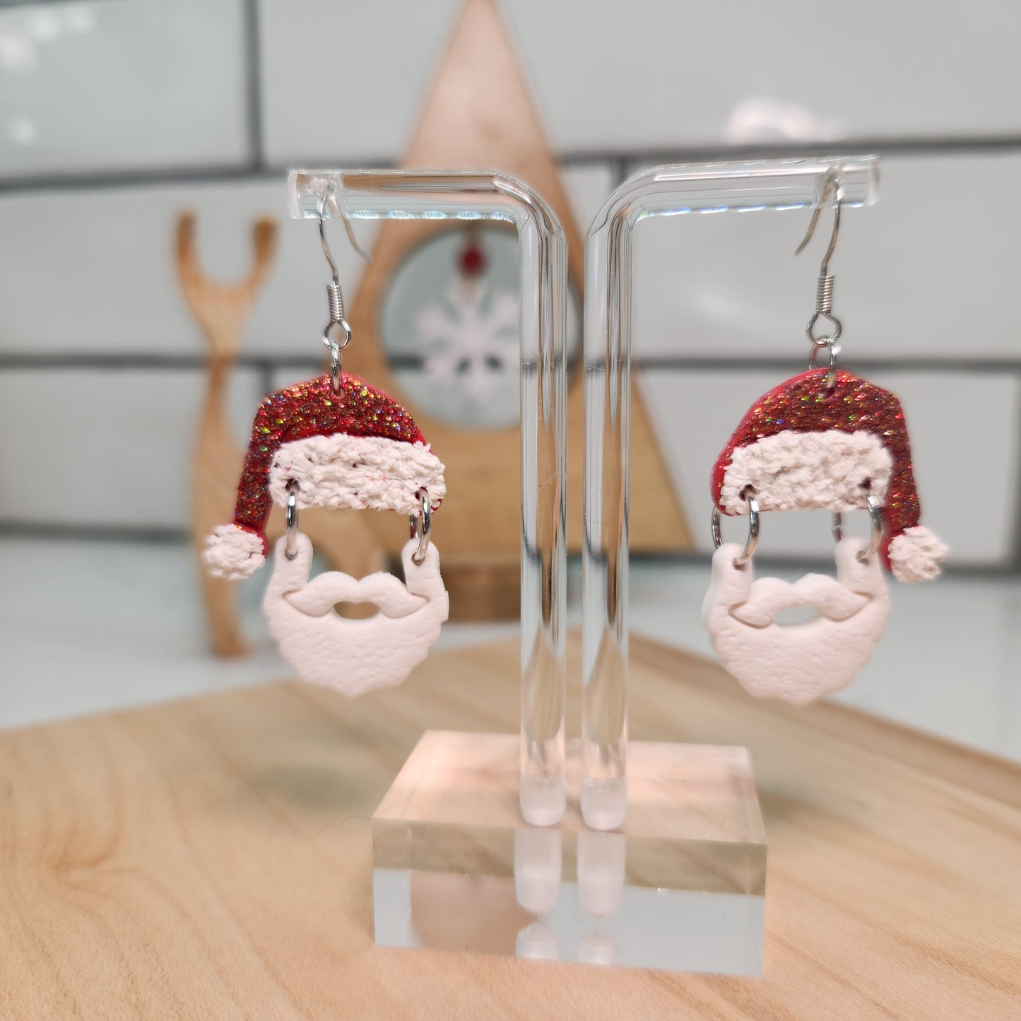 Pair of earrings with Santa Claus design on a clear stand.